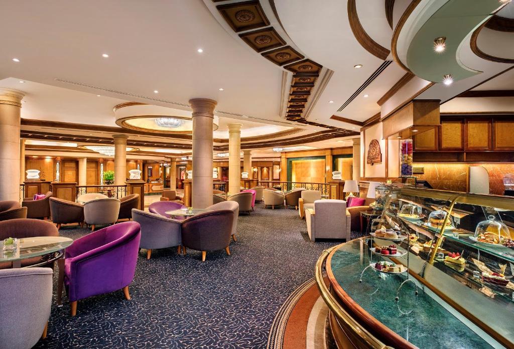 a hotel lobby with tables and chairs and a game room at Crowne Plaza Bahrain by IHG in Manama