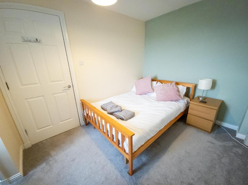 a bedroom with a bed with white sheets and pink pillows at Tranquil 2Bed/2Bath Duplex Falkirk in Falkirk