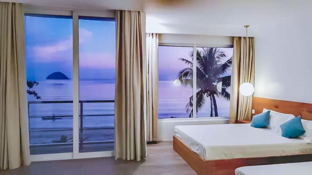 een slaapkamer met een groot raam met uitzicht op de oceaan bij Romblon Beach and Dive Resort in Romblon