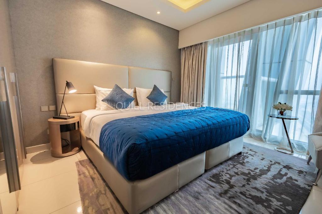 a bedroom with a large bed with a blue blanket at Quill Residence at Paramount Towers 3 BR Creek View in Dubai