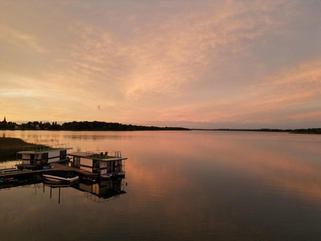 un muelle con un barco en un lago al atardecer en Boathousing - apartament na wodzie, dom pływający, łódź, luksusowy apartament, en Myślibórz