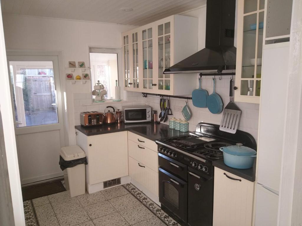 a kitchen with white cabinets and a black stove top oven at Gorgeous Gorleston holiday home in Gorleston-on-Sea