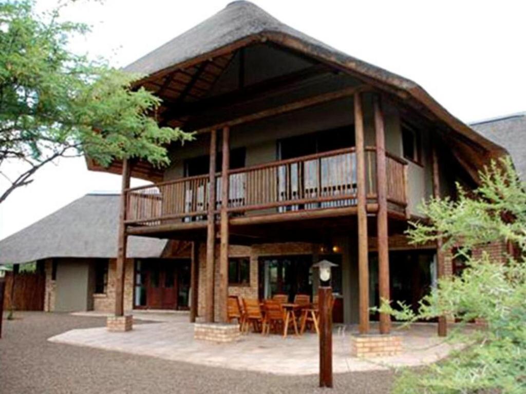 Sondela Nature Reserve & Spa Makhato Lodges في بيلا بيلا: منزل كبير مع شرفة مع طاولات وكراسي