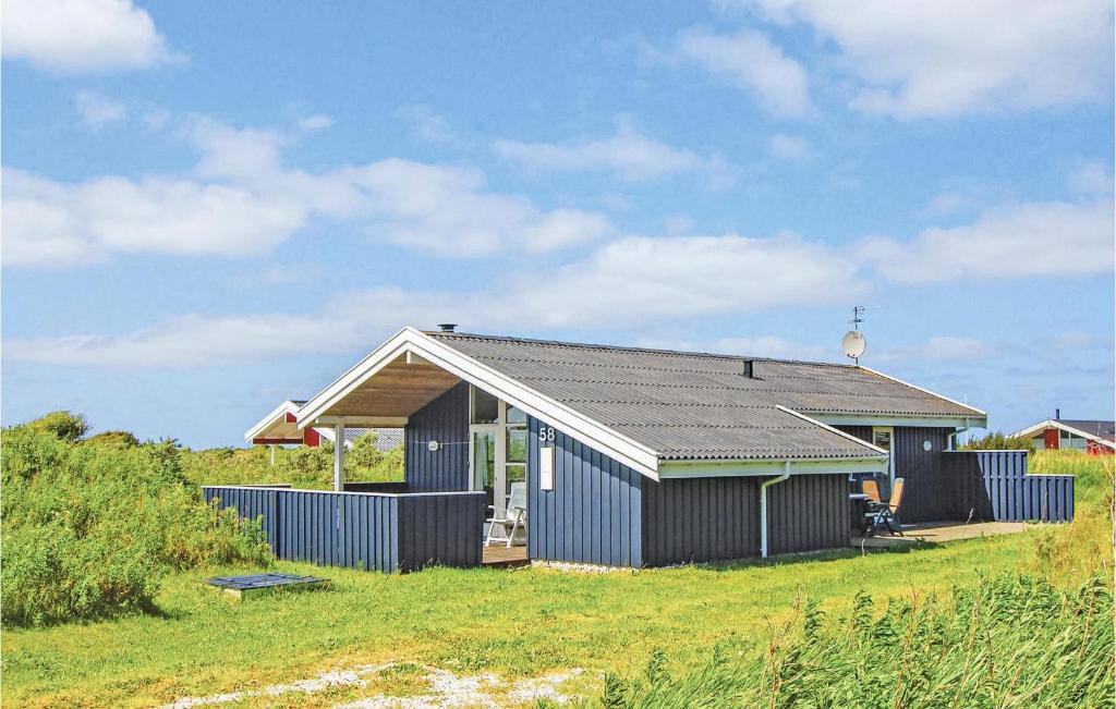 a small black house on a grass field at Nice Home In Hjrring With 3 Bedrooms And Wifi in Lønstrup