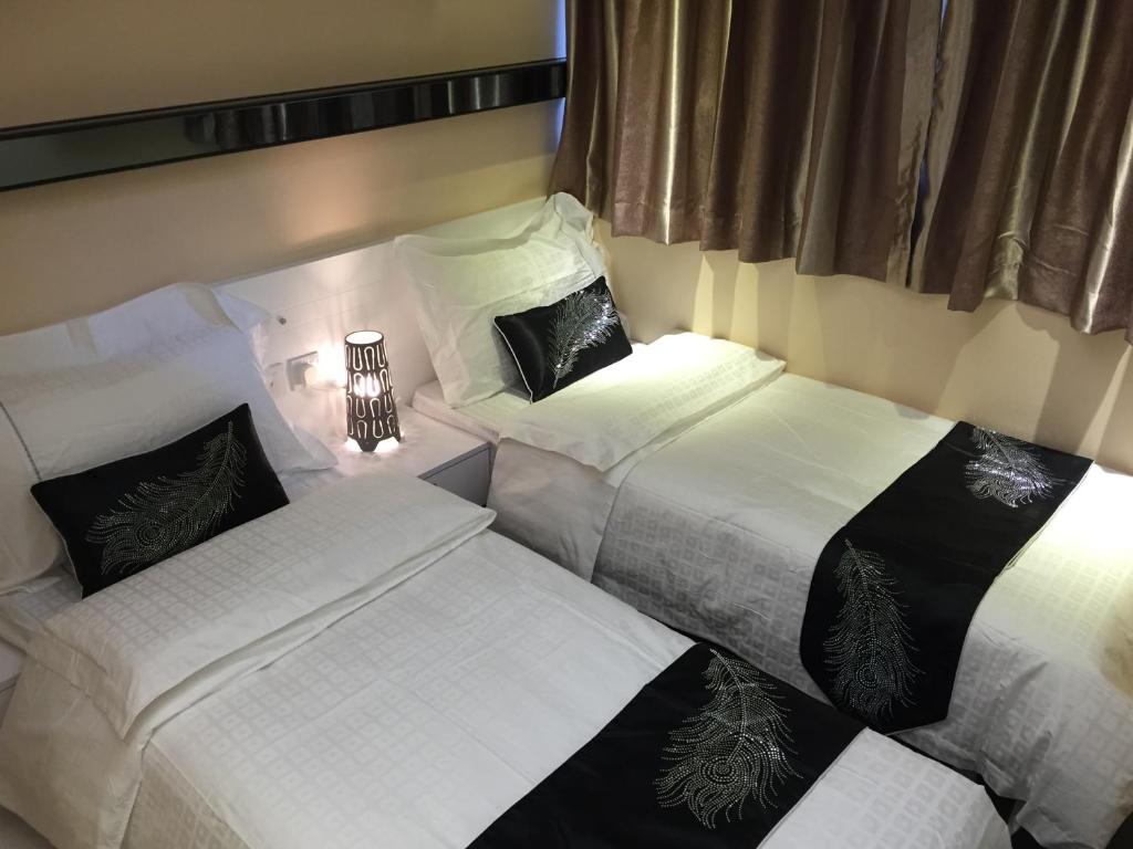1 dormitorio con 3 camas con sábanas blancas en Seasons Hotel - Causeway Bay, en Hong Kong