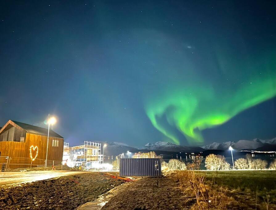 una aurora en el cielo sobre una ciudad por la noche en Villa Nordheim en Tromsø