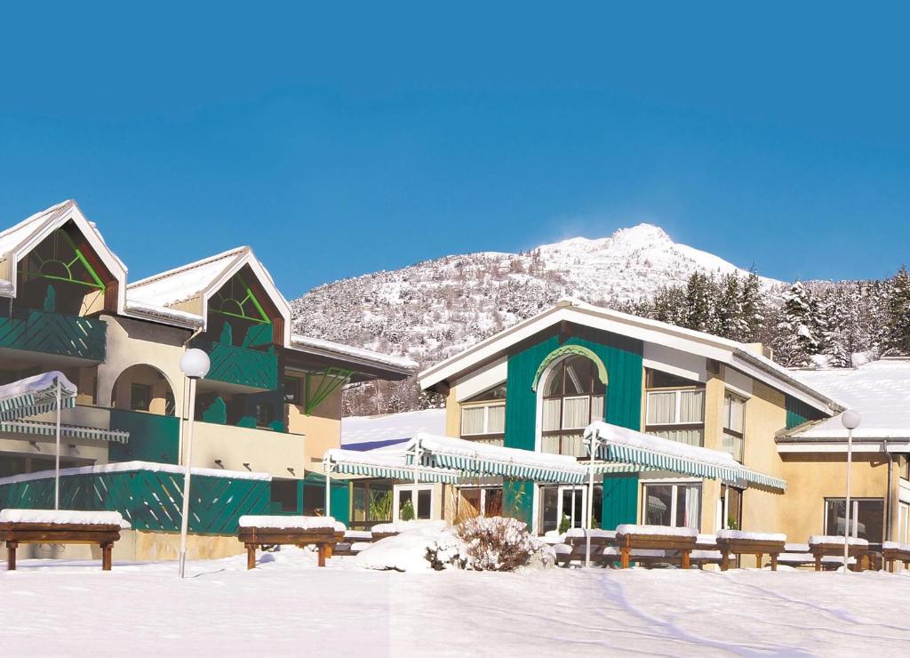 a building in the snow with benches in front of it at Club Vacances Bleues Les Alpes d'Azur in La Salle Les Alpes