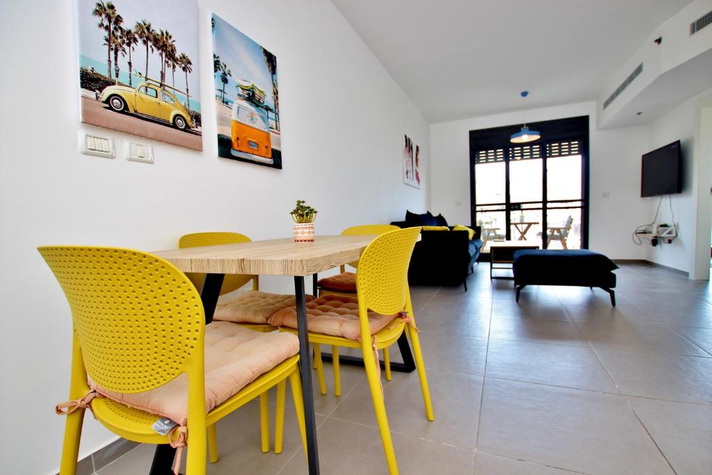 jadalnia ze stołem i żółtymi krzesłami w obiekcie beautiful 2 bedrooms apartment with balcony w Tel Awiwie