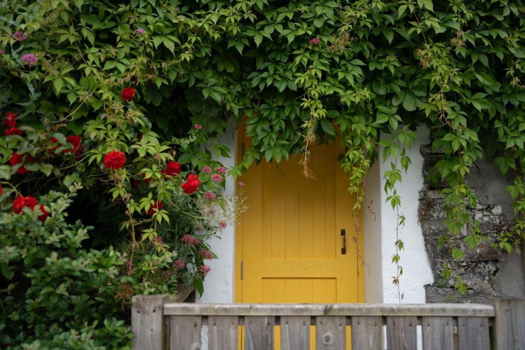 a yellow door on a house with flowers at The Roost in Westport