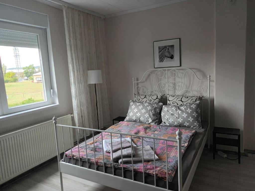 una camera da letto con letto in metallo, cuscini e finestra di Kuća Jovanka a Zaječar