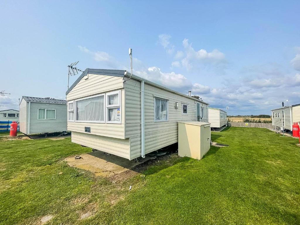 a tiny house sitting in a grass field at Superb Caravan With Free Wifi At Seawick Holiday Park Ref 27022s in Clacton-on-Sea