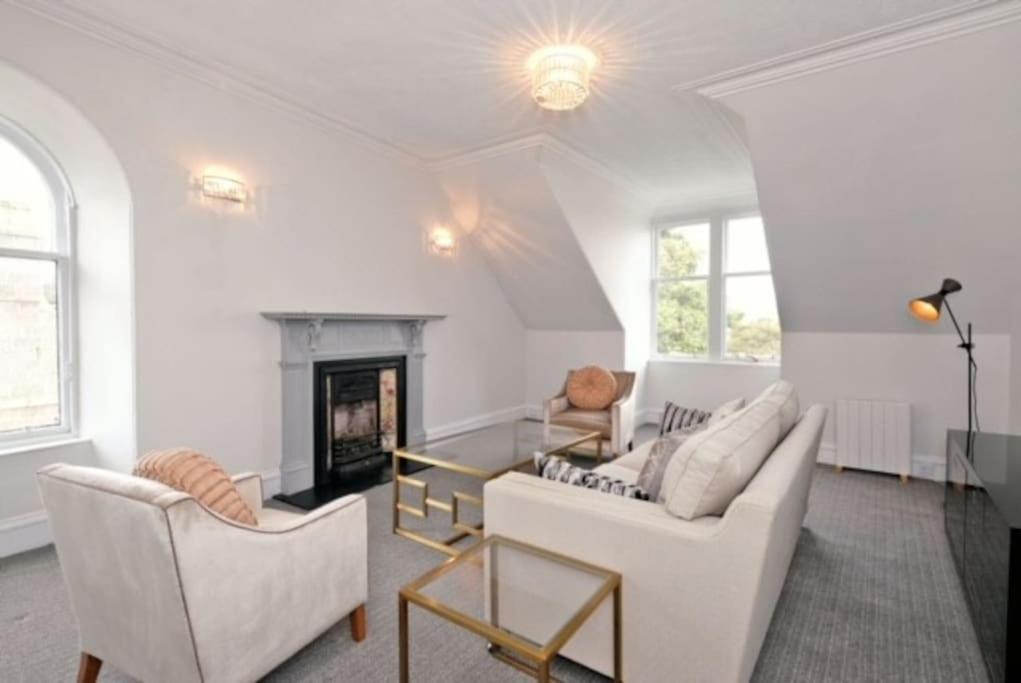 a living room with white furniture and a fireplace at Luxury West End Apartment in Aberdeen