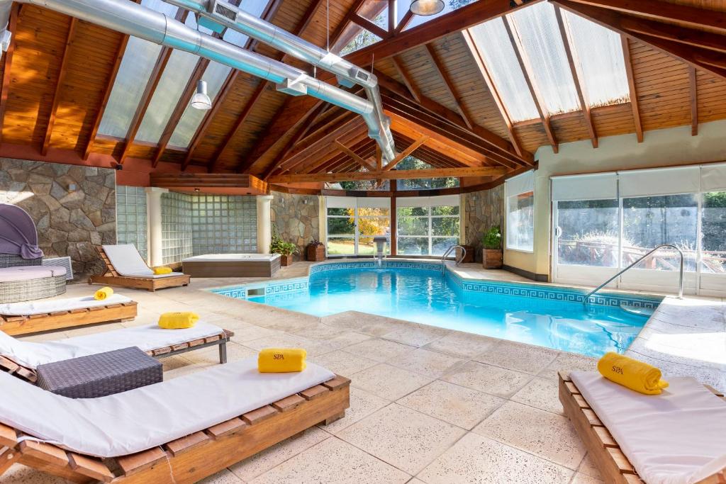 uma piscina interior com duas camas e uma casa de piscina em Resort de montaña - La Comarca em Villa La Angostura