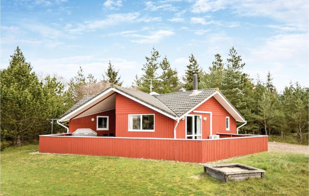 une maison rouge avec une clôture rouge dans une cour dans l'établissement Cozy Home In Blvand With Kitchen, à Blåvand