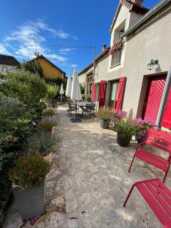un patio avec un banc rouge et une table avec des parasols dans l'établissement Bienvenue à Champlay, à Champlay