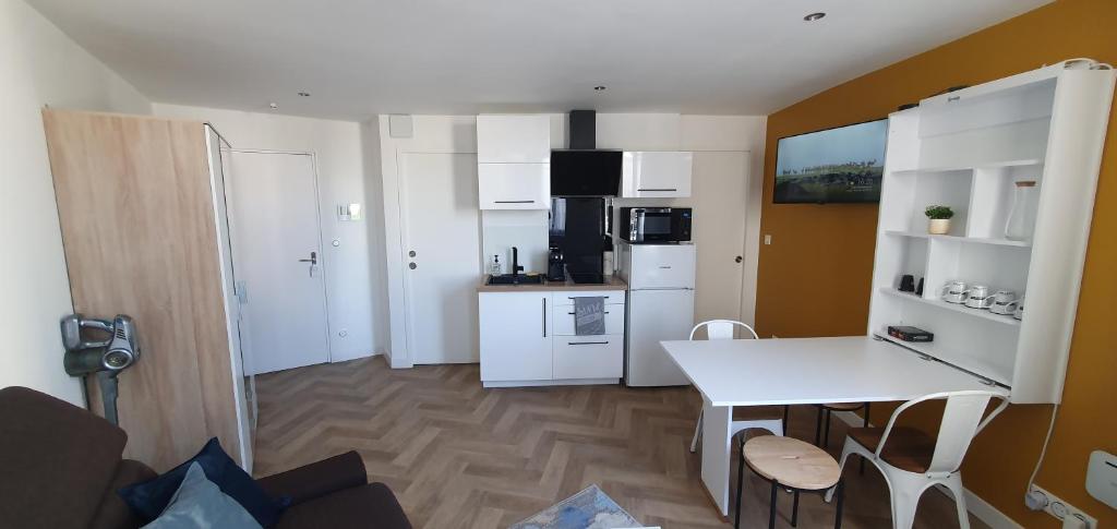 una cucina con mobili bianchi, tavolo e sedie di Appart Cosy Place Saint-Jean a Niort