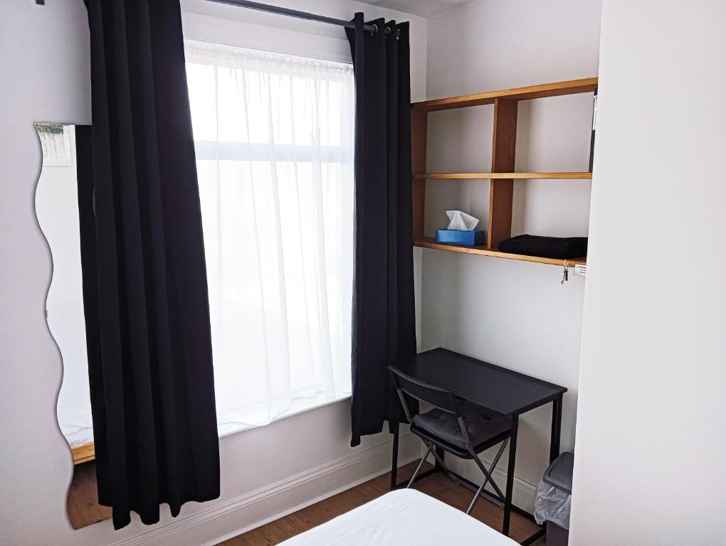 a bedroom with a window with black curtains and a desk at Maison Blanc in Nottingham