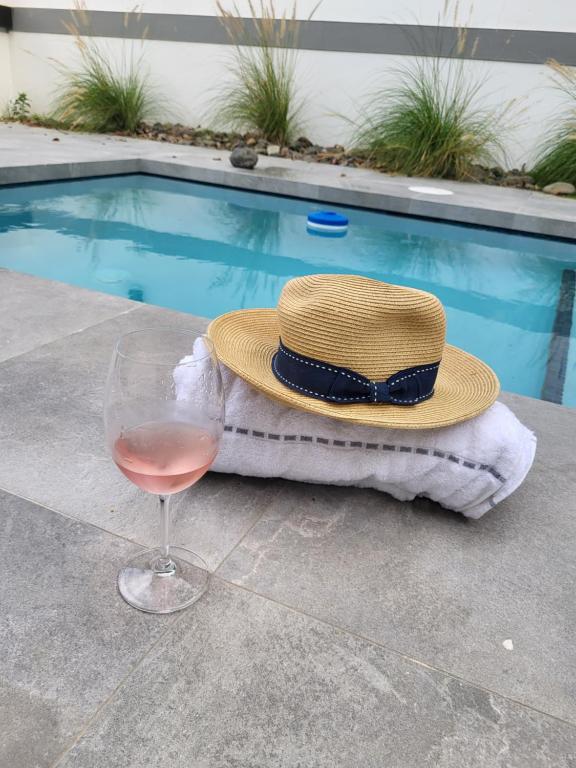 - un chapeau et un verre de vin à côté de la piscine dans l'établissement Le'Oasis Villa, à Juncos