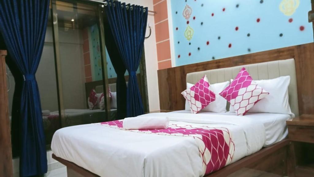 um quarto com uma cama com lençóis brancos e almofadas cor-de-rosa em HOTEL OM SAI em Vovale