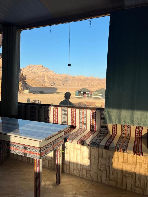 a table and benches in a room with a view of the desert at Adam Bedouin camp in Wadi Rum