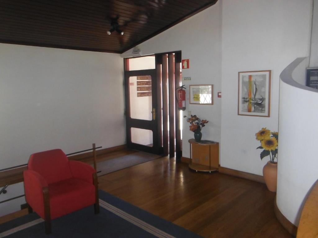uma sala de estar com uma cadeira vermelha e uma porta em Hotel Alameda em Albergaria-a-Velha