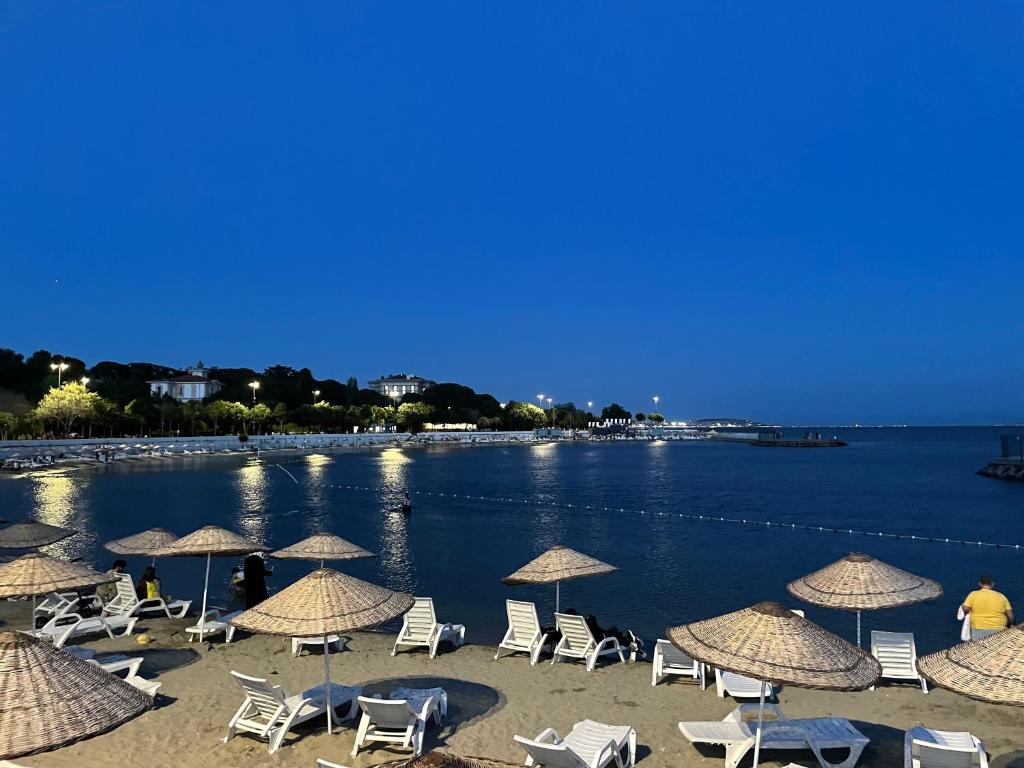 un grupo de sillas y sombrillas en una playa en Bağdat Caddesi'ne çok yakın huzurlu ve rahat ev, en Estambul