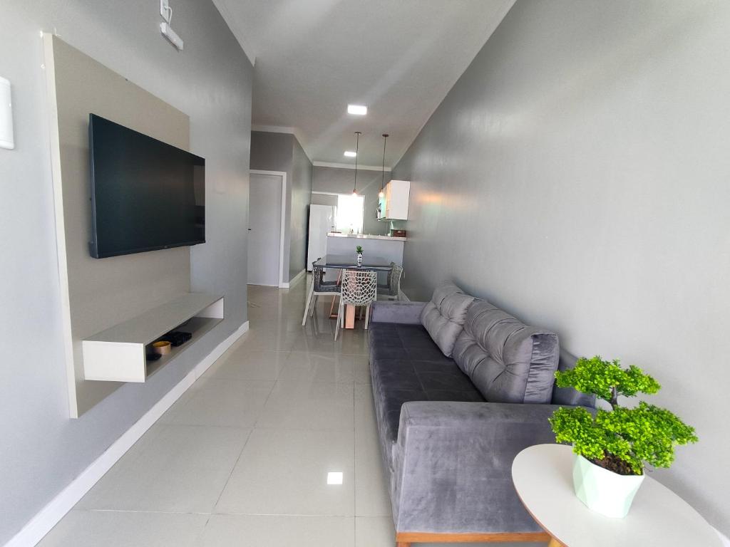 a living room with a couch and a tv on a wall at Dunas Residence - Casa 10 in Santo Amaro