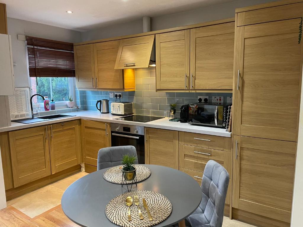a kitchen with wooden cabinets and a table and chairs at 2 Bedroom Apartment Chiswick Park Tube Station in London