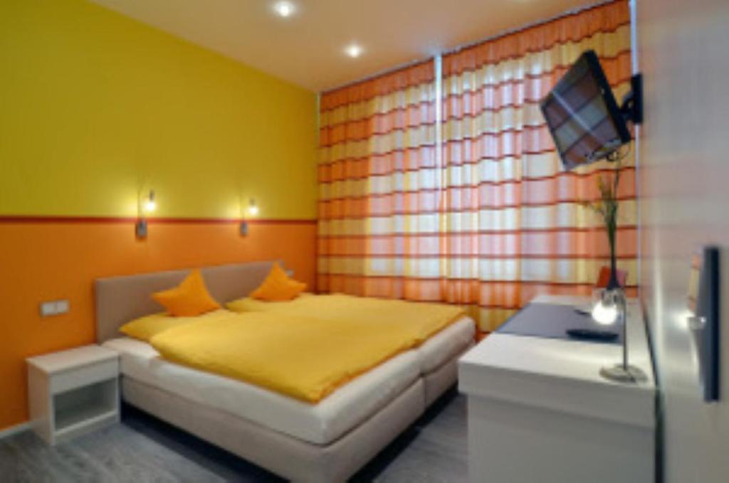 Schlafzimmer mit einem Bett und einem Schreibtisch mit einem TV in der Unterkunft Hotel am Bahnhof in Aachen