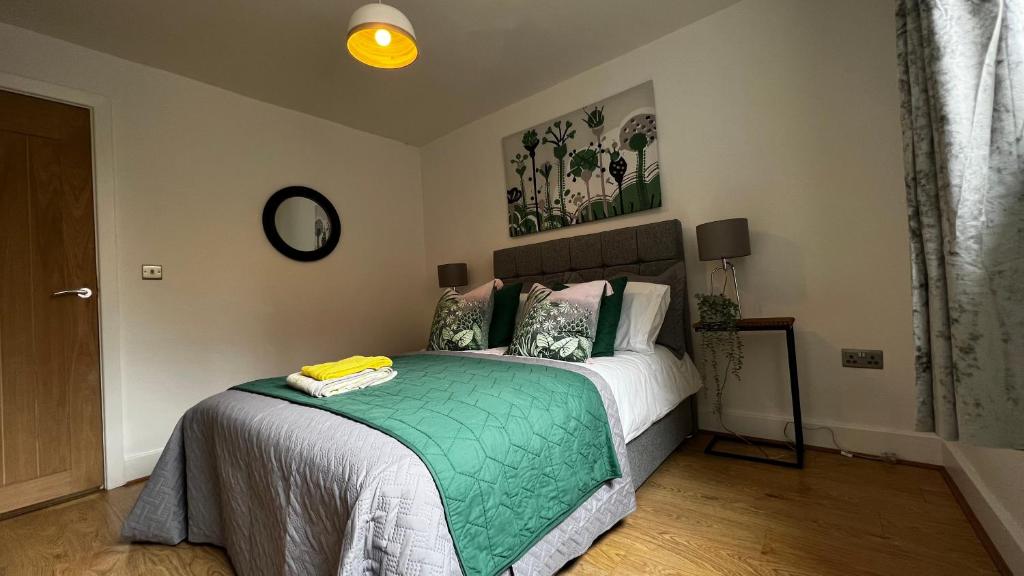 a bedroom with a bed with a green blanket at The Church View, Great for Contractors and groups, Easy access M1 in Markyatestreet
