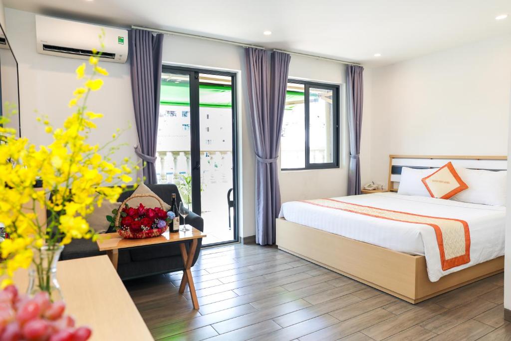 a hotel room with a bed and a table with flowers at Warm Ways Hotel & Serviced Apartments in Ho Chi Minh City