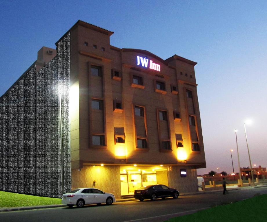 ein Gebäude mit zwei davor geparkt in der Unterkunft JW Inn Hotel in Khobar