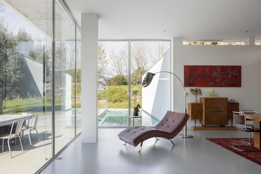 a living room with a table and chairs and glass walls at Casa Briteiros in Guimarães