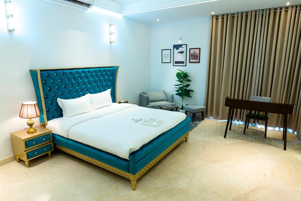 Palm Tree Business Hotel-孟加拉椰林国际商务酒店 في داكا: غرفة نوم بسرير ازرق مع مكتب وبيانو