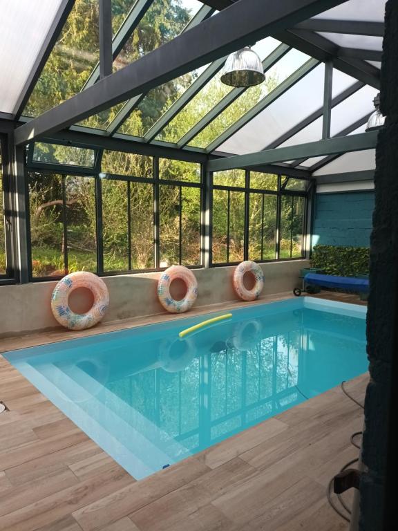 una piscina en una casa con techo de cristal en Au Domaine de Sophie piscine chauffée couverte et jacuzzi couvert, en Crasville