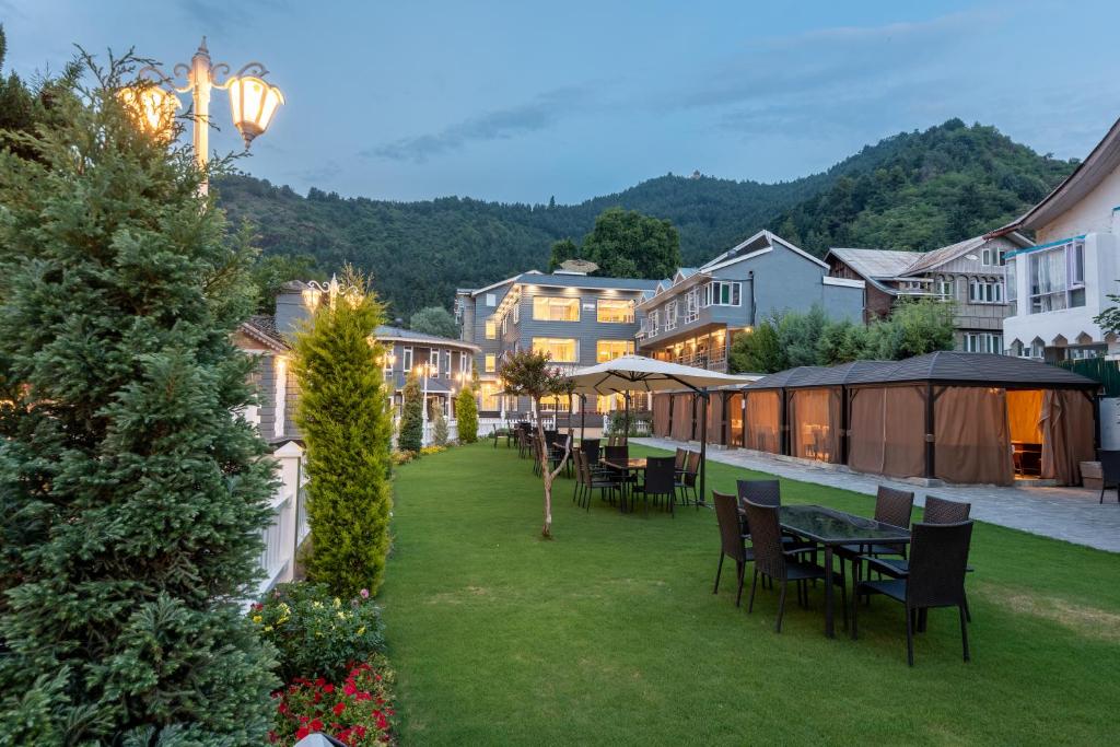 a patio with tables and chairs on a lawn at Hotel Grand Boulevard Dal Lake View Srinagar in Srinagar