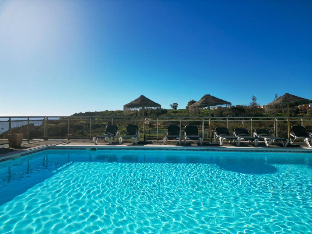 a large swimming pool with chairs and umbrellas at Carvi Beach Hotel in Lagos