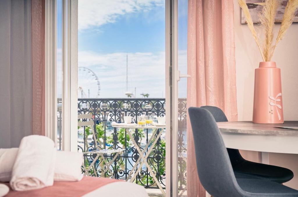 um quarto com uma secretária e uma varanda com vista em Hotel du Vieux Port em Saint-Raphaël