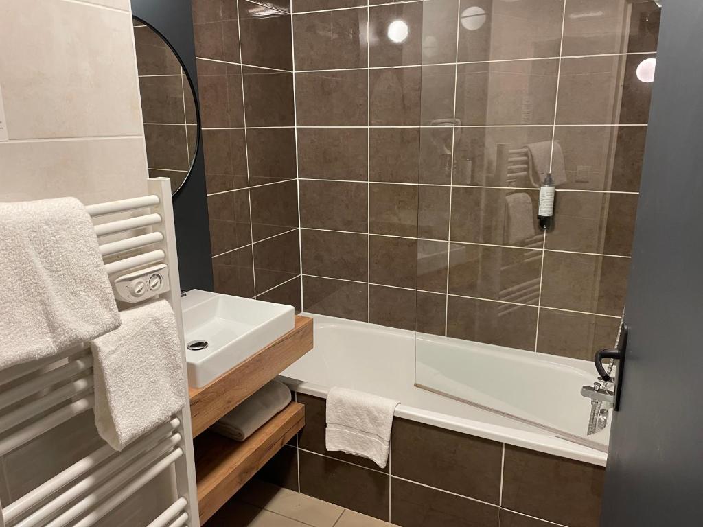 La salle de bains est pourvue d'une douche, d'un lavabo et d'une baignoire. dans l'établissement Odalys City Lyon Bioparc, à Lyon