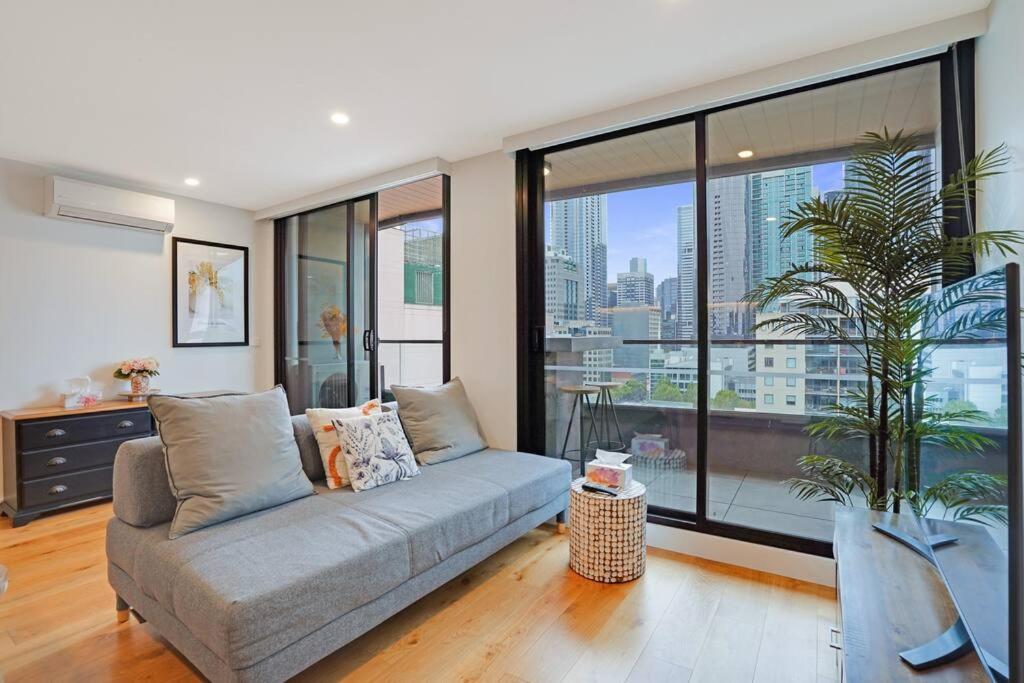 sala de estar con sofá y ventana grande en Bright 2B apt next to Flagstaff Garden freeparking#FG1003, en Melbourne