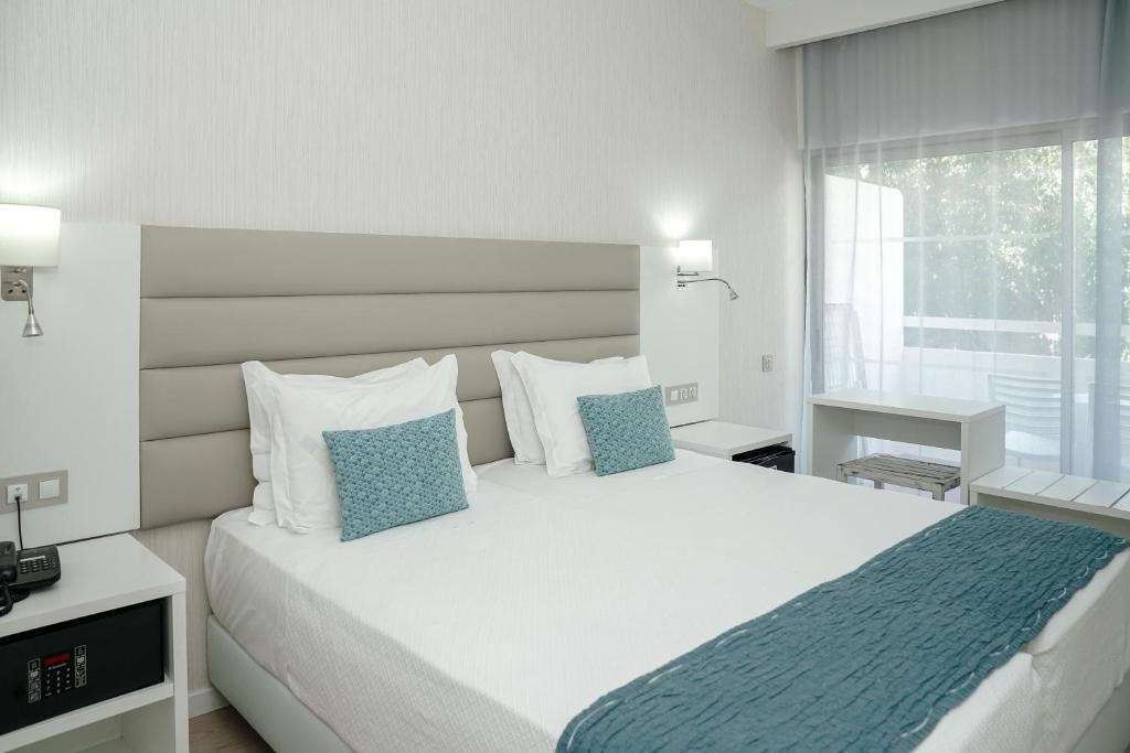 a bedroom with a large white bed with blue pillows at Carvi Beach Hotel in Lagos
