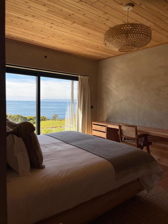 ein Schlafzimmer mit einem großen Bett und einem großen Fenster in der Unterkunft Casa da Figueira in São Roque do Pico