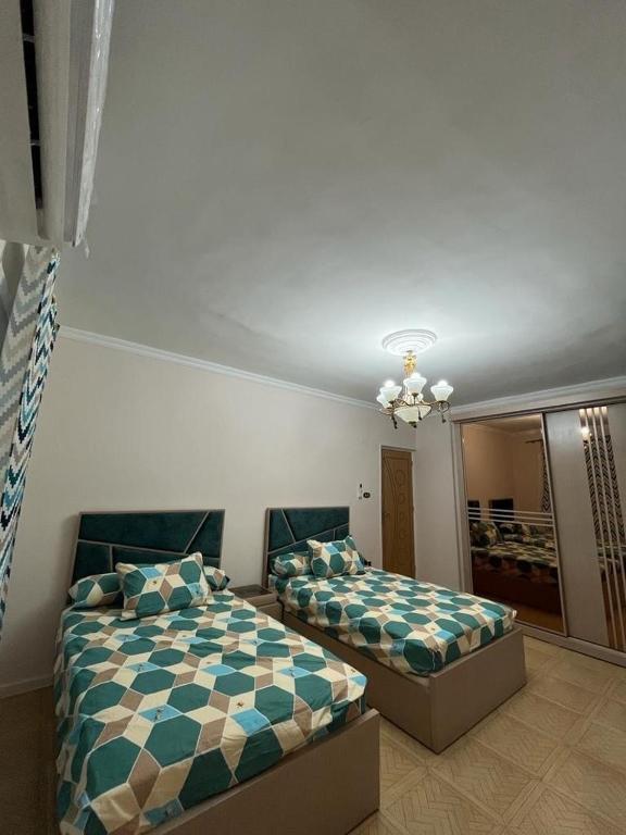 - une chambre avec 2 lits et un lustre dans l'établissement شقة مريحة بدمياط الجديدة, à Naj‘ al Jabāylah