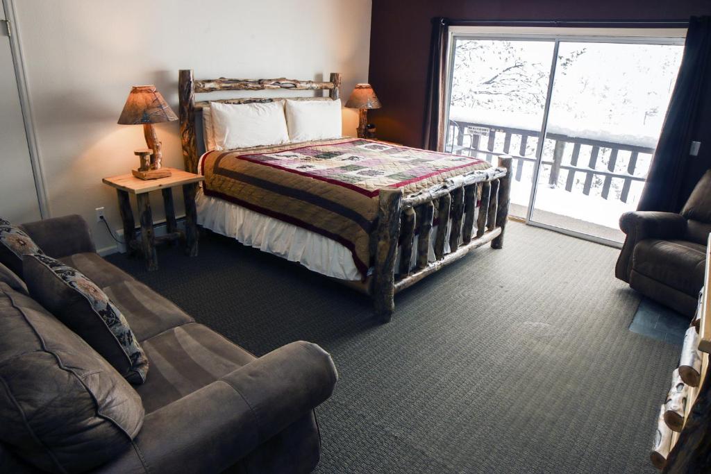 een slaapkamer met een bed, een bank en een raam bij Fawn Valley Inn- 304 condo in Estes Park
