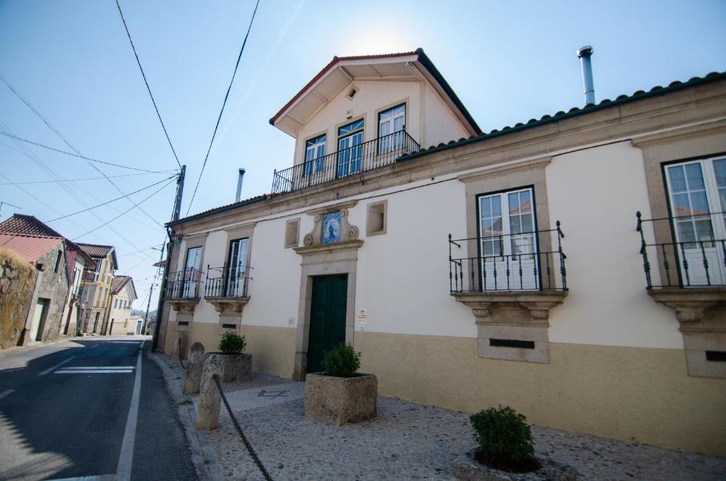 - un bâtiment blanc avec balcon dans une rue dans l'établissement Casa do Compasso, à Farminhão
