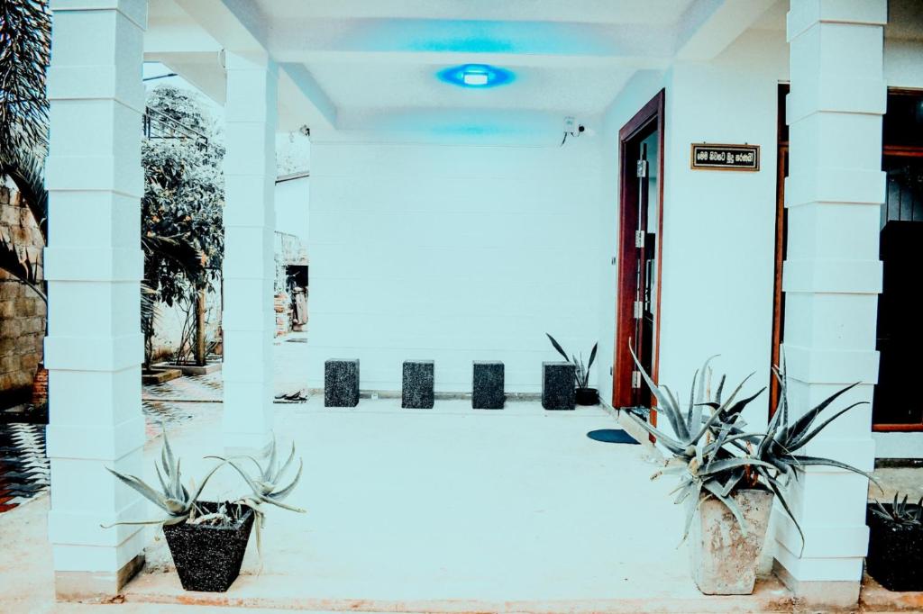 a white building with two potted plants in front of it at Pearl Residence in Weligama