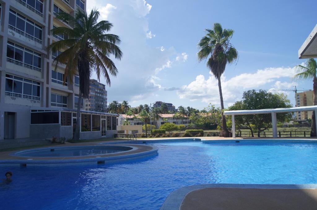 una gran piscina junto a un edificio con palmeras en Nautica Beach - Moderno Apartmento Margarita, en Porlamar