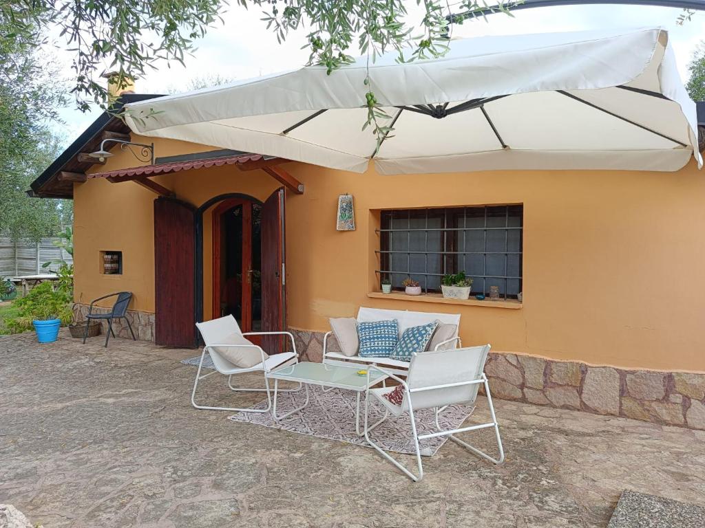 un patio con sillas y una sombrilla frente a una casa en Aspromonte Yellow House, en Bitonto