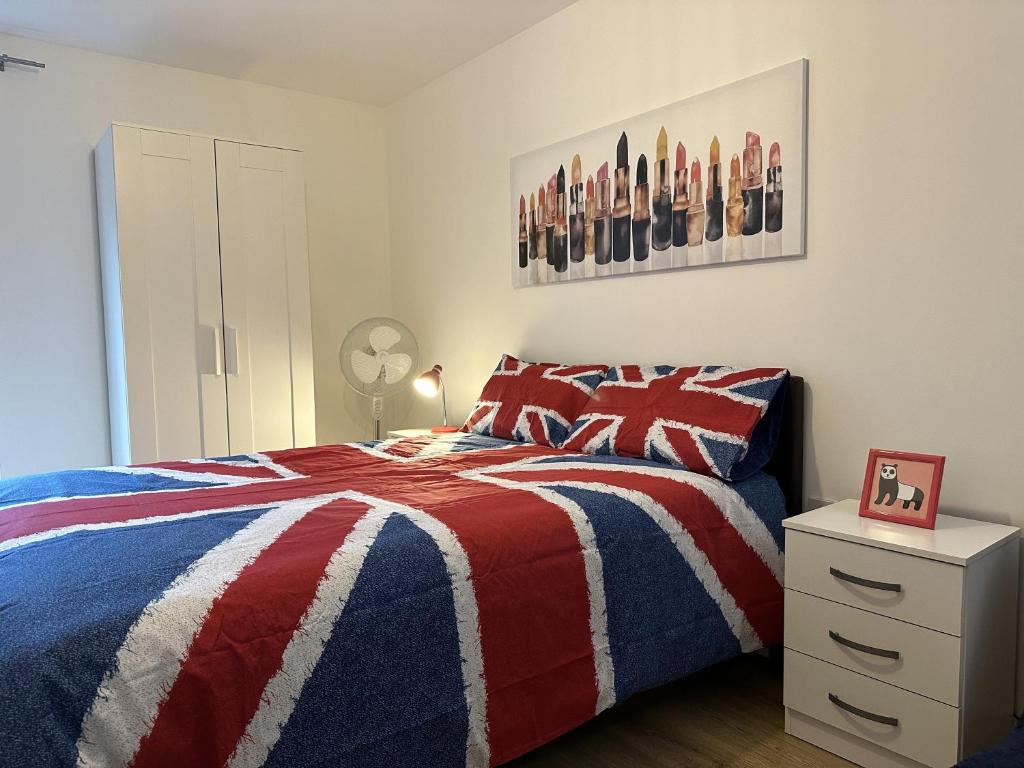- une chambre avec un lit rouge blanc et bleu et une table de chevet dans l'établissement Modern, Large Independent Room with En-suite Bathroom in Private Owned Apartment, à Londres