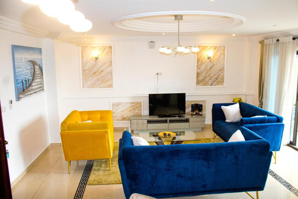 杜阿拉的住宿－Residence Le Carat Bonapriso，客厅配有蓝色的沙发和黄色的椅子